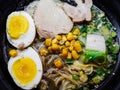 Shio ramen with egg, noodles and chicken in a dark dish close-up