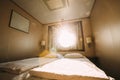 Ship Cabin With Bed And Window With View On Sea. Luxury Cabin On Ferry Boat Or Cruise Liner. Sunset Sun Shine Through Royalty Free Stock Photo