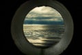 Ship window or porthole view with a relaxing seascape and dark grey clouds Royalty Free Stock Photo