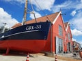 A ship and colorful fishermenâs cottages at the harbour in Zoutkamp, Groningen