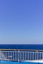 Ship deck railing  while sailing on open sea. Vivid blue color with copy space Royalty Free Stock Photo