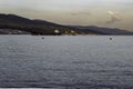 The ship enters the bay at the port at sunset against the backdrop of mountains