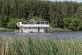 A ship in the form of a two-story houseboat floats along the river. Cruise on the river. Summer outdoor recreation