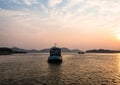 Ship heading towards river island at dusk orange sky Royalty Free Stock Photo