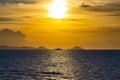 Ship on the horizon between the island and mainland in front of the rising sun