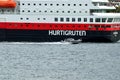 The ship hurtigruten entering tromsoe harbour with speeding small boat passing it Royalty Free Stock Photo