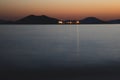 ship passing between mountains summer night, orange sky, calm sea, light reflections, black mountains, sea