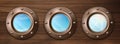 Ship portholes on wooden wall with sky view
