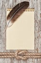 Ship rope, feather, spiral notebook and wood background Royalty Free Stock Photo