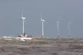 Ship on rough sea horizon by offshore wind farm turbines Royalty Free Stock Photo