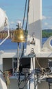 The ship`s bell on the bow with elements of the rigging of the ship on a Sunny day vertically