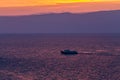 Ship sails on a background of purple sunset sky on the waves of Lake Baikal from Olkhon