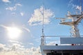 Ship structures, masts, antennas, funnel, ship wheelhouse against the blue sky and clouds.