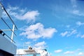 Ship structures, masts, antennas, funnel, ship wheelhouse against the blue sky and clouds.