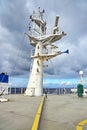 Ship structures, masts, antennas, funnel, ship wheelhouse against the blue sky and clouds.