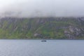 Ship to visit fjords in Norway. A mystical fjord with dark clouds in Norway with mountains and fog hanging over the water Royalty Free Stock Photo