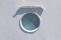 Ship window or porthole on white metall wall with cross.