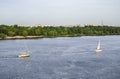 Ship yachts with white sails in the Dnipro river on a background of the Kyiv city landscape