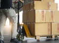 Shipment boxes, Warehousing. Worker working with hand pallet truck unloading cargo boxes on pallet at the warehouse. Royalty Free Stock Photo