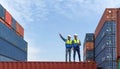 Shipment worker use a walkietalkie to point to container storage location, explain to colleague about planning for next shipment.