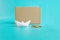 Shipping cheap cargo concept. Paper ship, coins and craft box front view isolated blue background