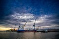 Cargo ship docked at industrial port, cranes ready for unloading. Shipping containers, maritime commerce. Sunset over Royalty Free Stock Photo