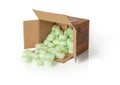 Shipping peanuts spilling out of the parcel box laying on its side, isolated on a white. Brown cardboard box with loose green foam