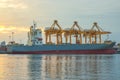 Shipping port with crane for container uploading at dusk