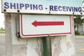 shipping receiving sign with long red arrow pointing left on metal post. p Royalty Free Stock Photo