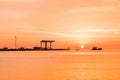 Ships and a boat in the sea near the pier on the background of an orange sunset. Repair dock Royalty Free Stock Photo