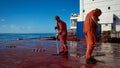 Ships crew members painting hatch cover outdoors with bright blue sky on a background. Ship maintenance concept