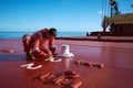 Ships crew members painting hatch cover outdoors with bright blue sky on a background. Ship maintenance concept
