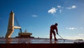 Ships crew members painting hatch cover outdoors with bright blue sky on a background. Ship maintenance concept