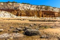 A shipwreck juts out from the sand on Old Hunstanton Beach beneath the white, red and orange cliffs in Norfolk, UK