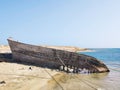 Shipwreck of old wooden ship fixed with laid ropes at beach