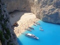 Shipwreck in the sand of a blue sea beach with other boats betwenn white montains -