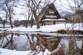 In Shirakawa village, a water reflection creates a poetic mirror image of a snow-covered thatched-roof cottage Royalty Free Stock Photo