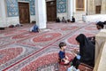 Islamic woman with child is sitting in courtyard of mosque.