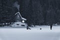 Shiroka poliana dam, Bulgaria. 03,02,2020: Small wooden house in the mountain. Frozen lake in front covered with snow. Ice fishing Royalty Free Stock Photo