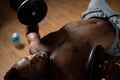 Shirtless afro american man doing exercises with dumbbells lying on bench in gym. Royalty Free Stock Photo