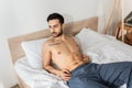 Shirtless bearded man lying on bed