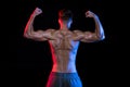 Shirtless bodybuilder gesturing isolated on black with dramatic lighting