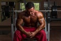 Shirtless bodybuilder resting at the bench