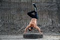 Shirtless bodybuilder training handstand on large wheel