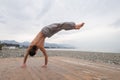 Shirtless caucasian man doing backflip on pebble beach. Royalty Free Stock Photo