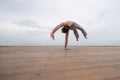 Shirtless caucasian man doing backflip on pebble beach. Royalty Free Stock Photo