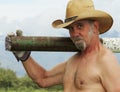 A Shirtless Cowboy Shoulders a Fence Post Driver