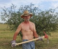 A Shirtless Cowboy Uses a Red Pickax