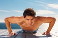 Shirtless guy doing push ups on a porch outdoors. Portrait of a healthy young masculine guy exercising on the porch.