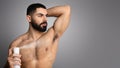 Shirtless handsome athletic middle eastern young man using deodorant Royalty Free Stock Photo